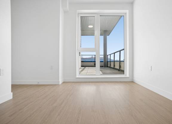 A room with a large window and wooden flooring.