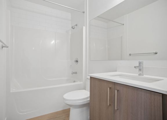 A white bathroom with a toilet, sink, and shower.