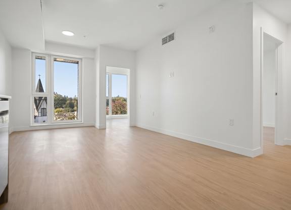A large empty room with wooden floors and white walls.