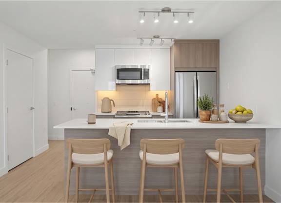 A modern kitchen with a white countertop and wooden bar stools.