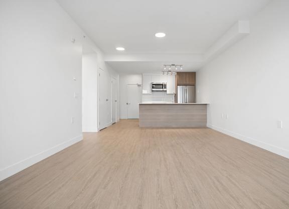 A large empty room with a wooden floor and white walls.