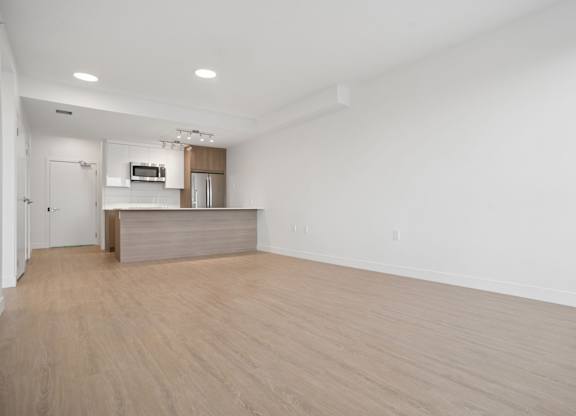 A spacious room with a kitchenette and a wooden floor.