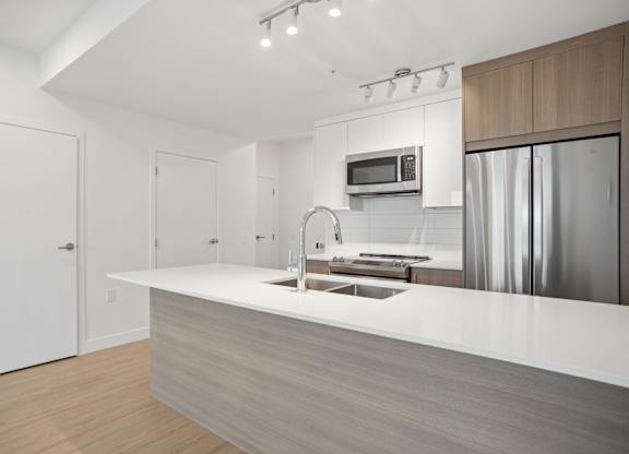 A modern kitchen with a white countertop and stainless steel appliances.