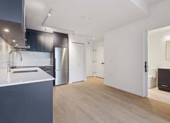 a kitchen and living room with white walls and wood floors