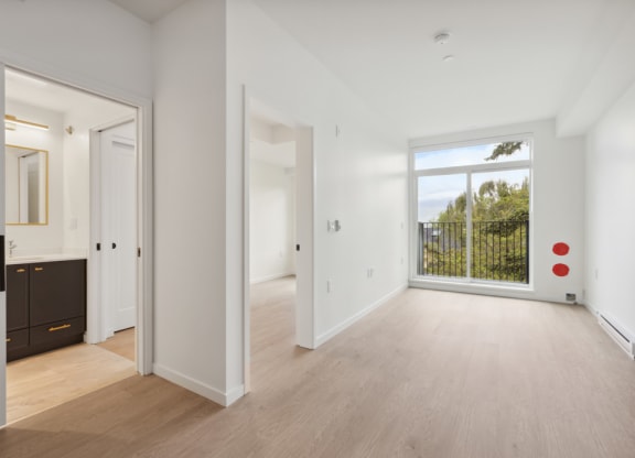 a living room with a large window and a door to a bedroom