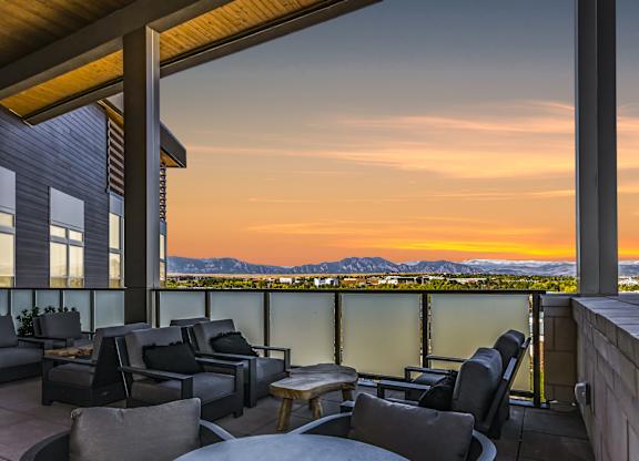 A patio with chairs and a table overlooking a sunset  at Bridges at Flatiron, Broomfield, 80021