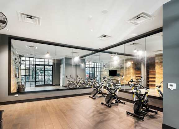 A gym with a mirror on the wall and exercise bikes  at Bridges at Flatiron, Broomfield, 80021