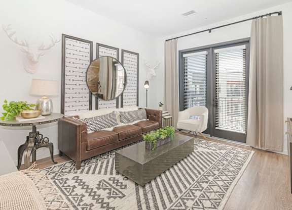 A living room with a brown couch, a coffee table, and a mirror on the wall  at Bridges at Flatiron, Broomfield, 80021