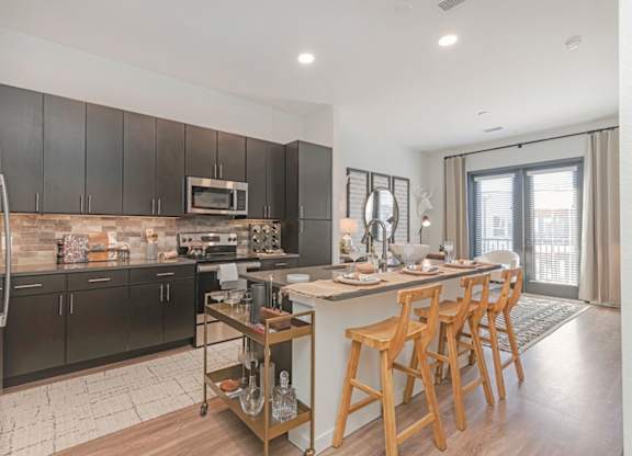 A modern kitchen with dark wood cabinets and a central island  at Bridges at Flatiron, Broomfield, 80021