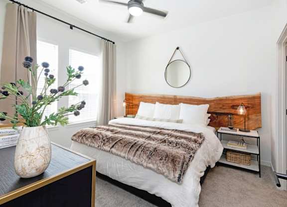A bedroom with a bed, a vase with flowers, and a ceiling fan  at Bridges at Flatiron, Broomfield, 80021.