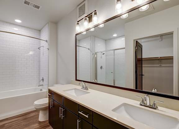 A bathroom with a white tiled shower and a white bathtub  at Bridges at Flatiron, Broomfield, 80021