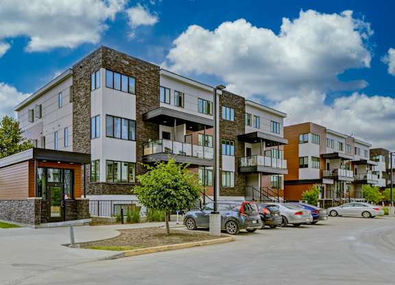A modern apartment complex with a parking lot in front.