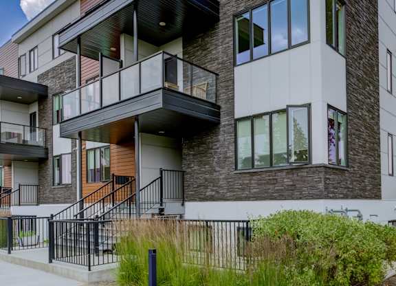 A modern two-story building with balconies and a mix of brick and siding exterior.