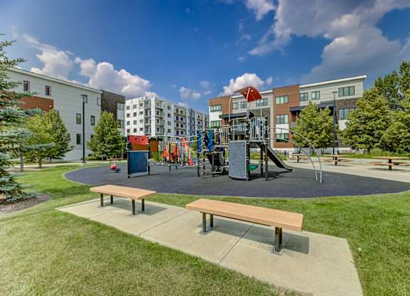 A playground with a slide and swings in front of a building.