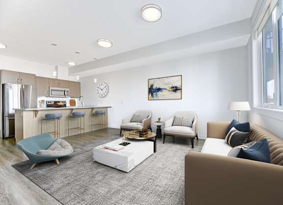 A modern living room with a kitchen area in the background.