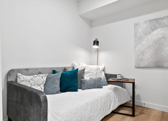 a bedroom with a bed and a nightstand with a clock and a painting on the wall