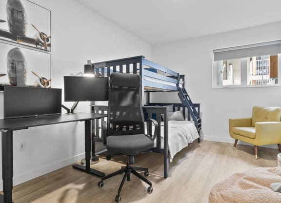 a bedroom with a bunk bed desk and chair
