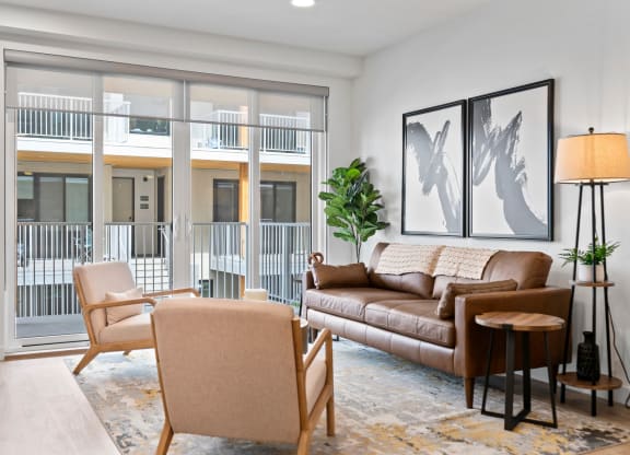 a living room with a couch chairs and a floor to ceiling window