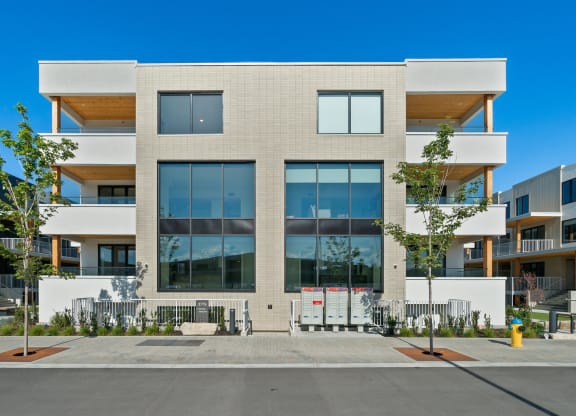 an apartment building with large windows and a sidewalk