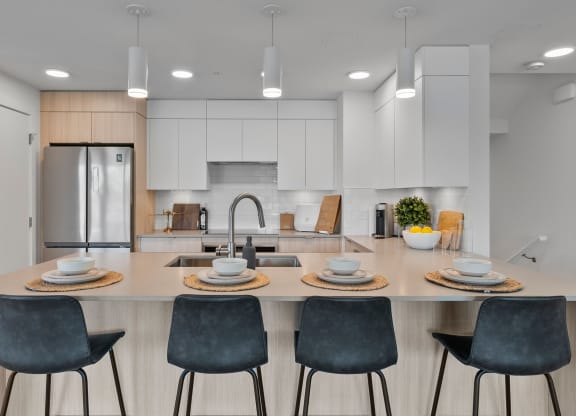 a kitchen with white cabinets and a large island with a sink and four chairs