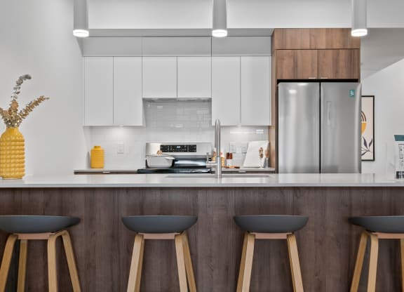 a kitchen with white cabinets and a large island with three stools in front of it