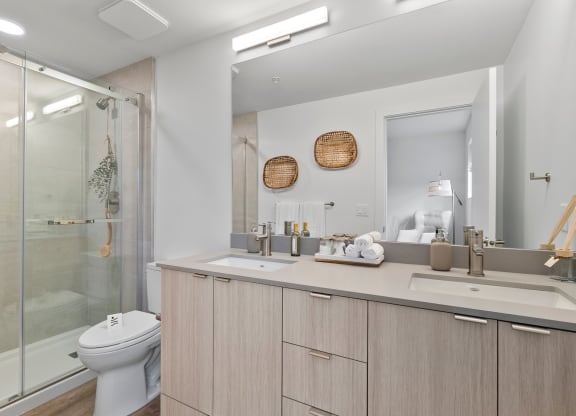 a bathroom with a toilet sink mirror and shower in a 555 waverly unit