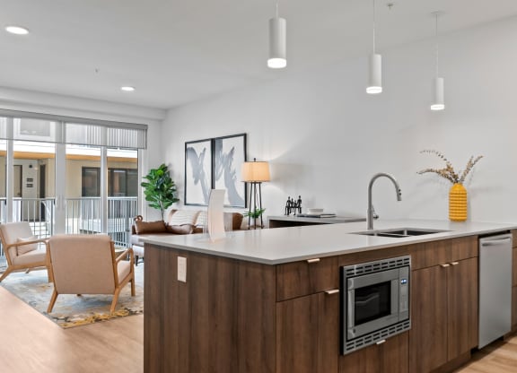 a kitchen with an island in front of a living room with a couch and chairs