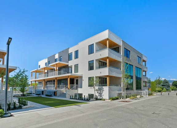a large white apartment building with balconies and a lawn