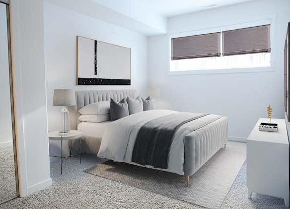 A bedroom with a large bed and a small table with a lamp on it.