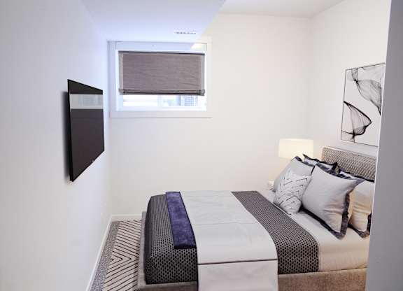A bedroom with a bed, pillows, and a window.