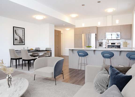 A modern living room with a kitchen in the background.