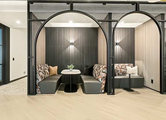 A modern room with a table and two chairs under a black arch.
