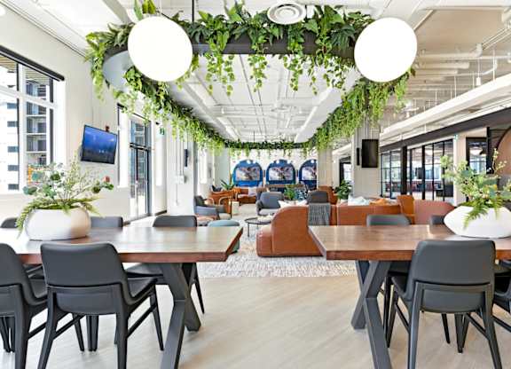 A modern dining area with wooden tables and grey chairs.
