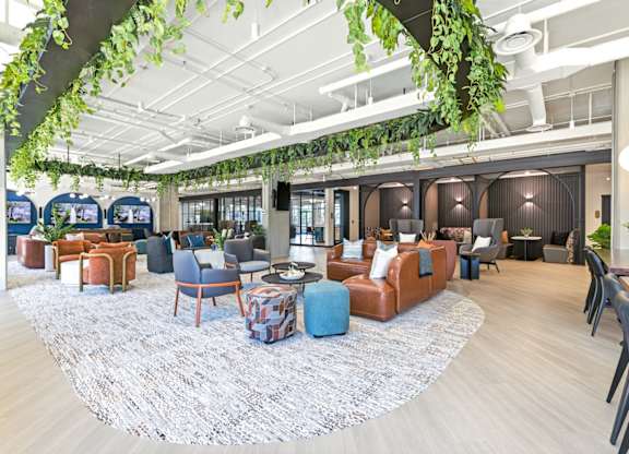 A modern lounge area with a variety of seating options and a large rug.