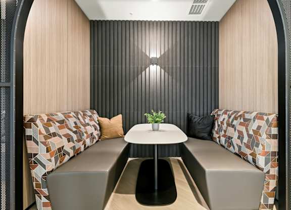 A small round table with a plant on it sits between two couches in a room with a striped wall.