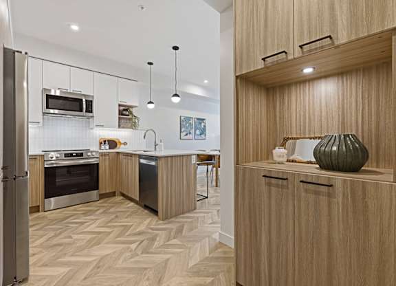 A modern kitchen with wooden cabinets and a herringbone patterned floor.