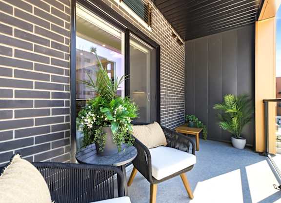 A patio with a black chair and a table with a potted plant on it.