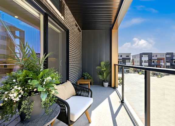 A balcony with a chair and a table with a potted plant on it.