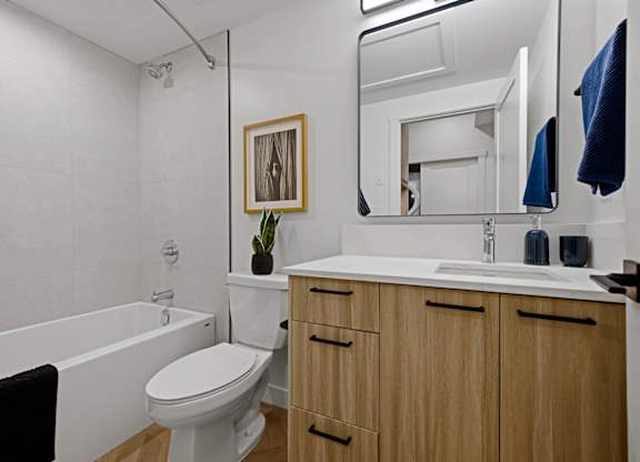 A bathroom with a toilet, sink, and mirror.
