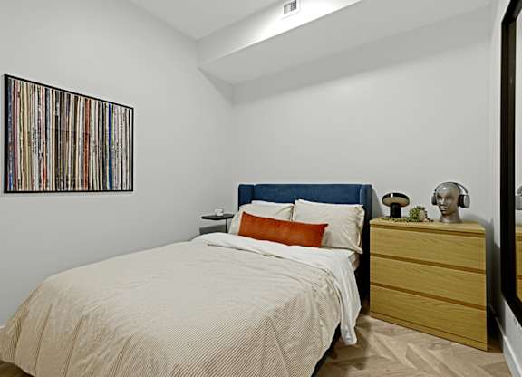 A bedroom with a bed, nightstand, and a picture on the wall.