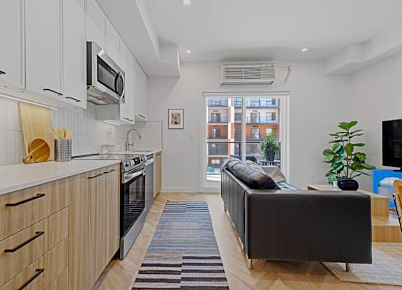 A modern kitchen with wooden cabinets and a black sofa.