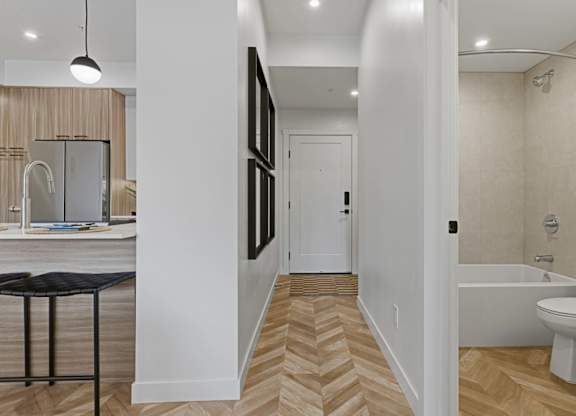 A bathroom with a white tub and a wooden floor.