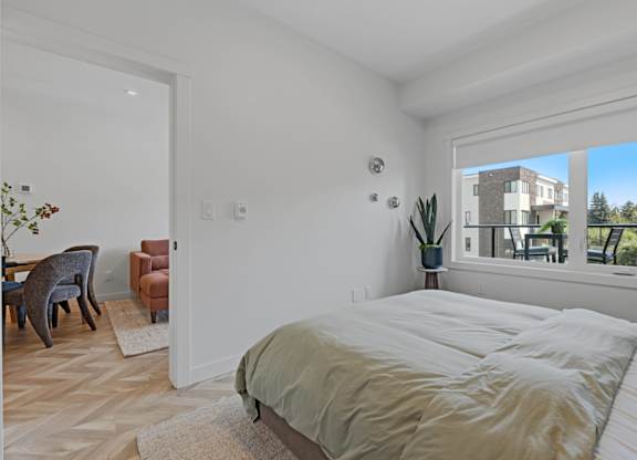 A bedroom with a large bed and a view of a building outside the window.