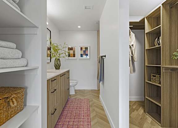 A bathroom with a towel on a shelf and a basket on the floor.