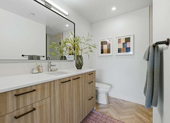 A bathroom with a white counter top and wooden cabinets.
