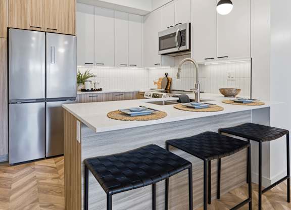 A kitchen with a white counter top and a refrigerator.