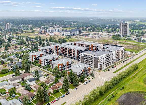 A large building complex is surrounded by a green field and other buildings.