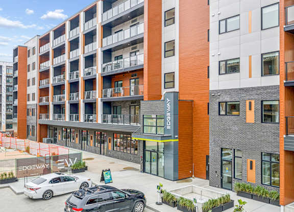 A modern apartment complex with cars parked in front.