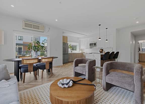A living room with a grey couch, a wooden coffee table, and a large window.