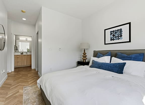 A bedroom with a large bed and a mirror on the wall.